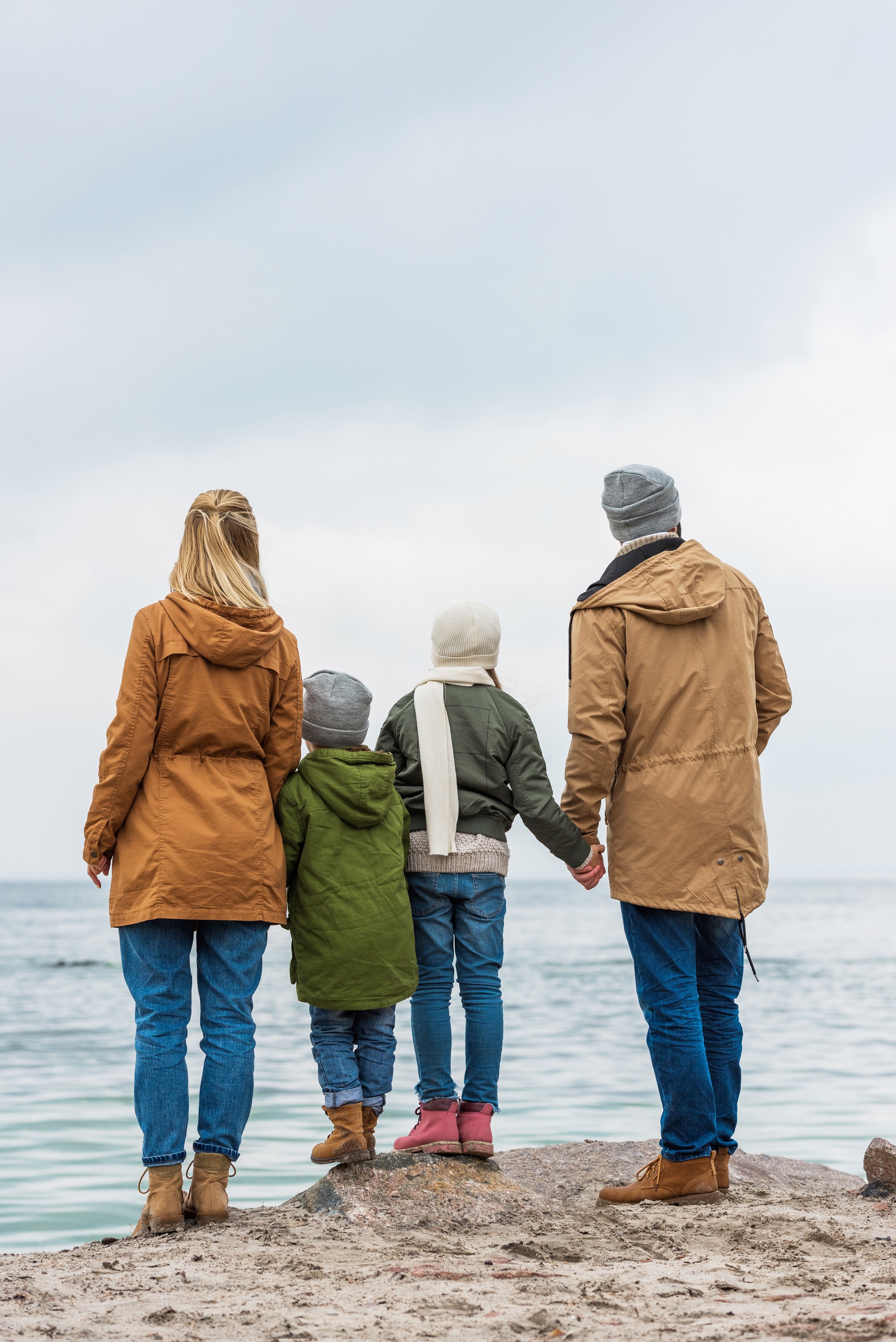 Familie på 4 står på en strand og kigger ud over havet